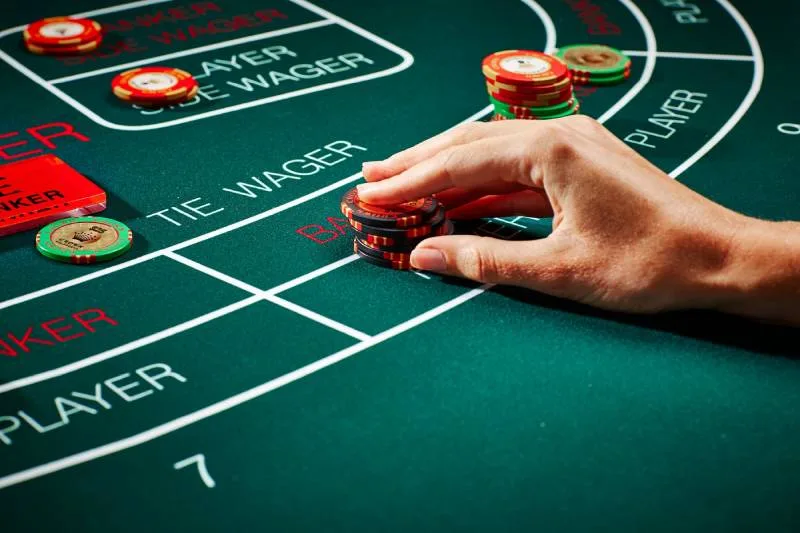 a hand placing poker chips on a green table