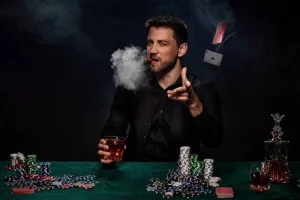 a man sitting at a table with cards and a cigar